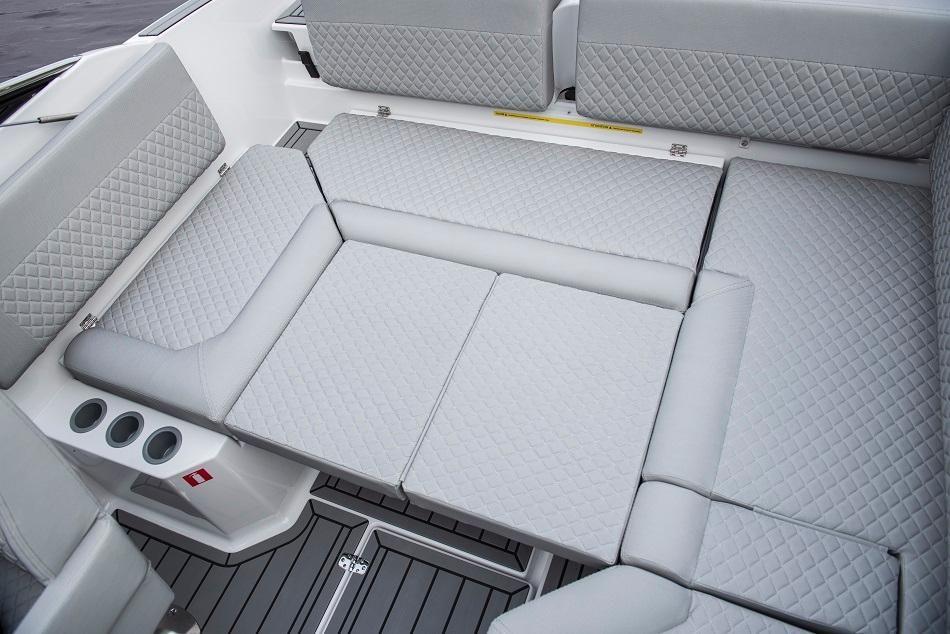 Interior of a boat featuring gray, quilted seating and cup holders on the side, with a sleek design and modern finish.